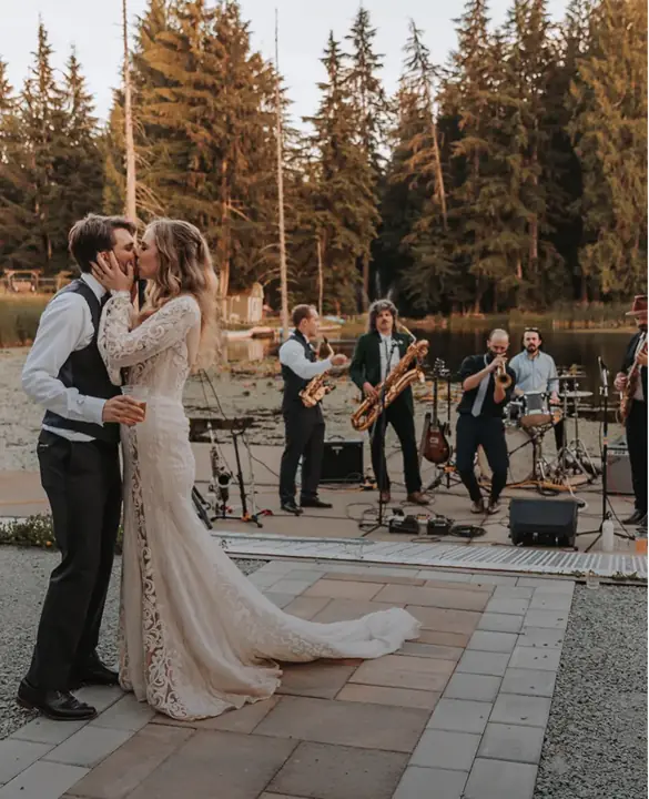 The newlyweds on the lakeside ceremony stage, with a live band playing by the water