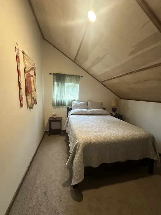 A bedroom under the slanted attic ceiling