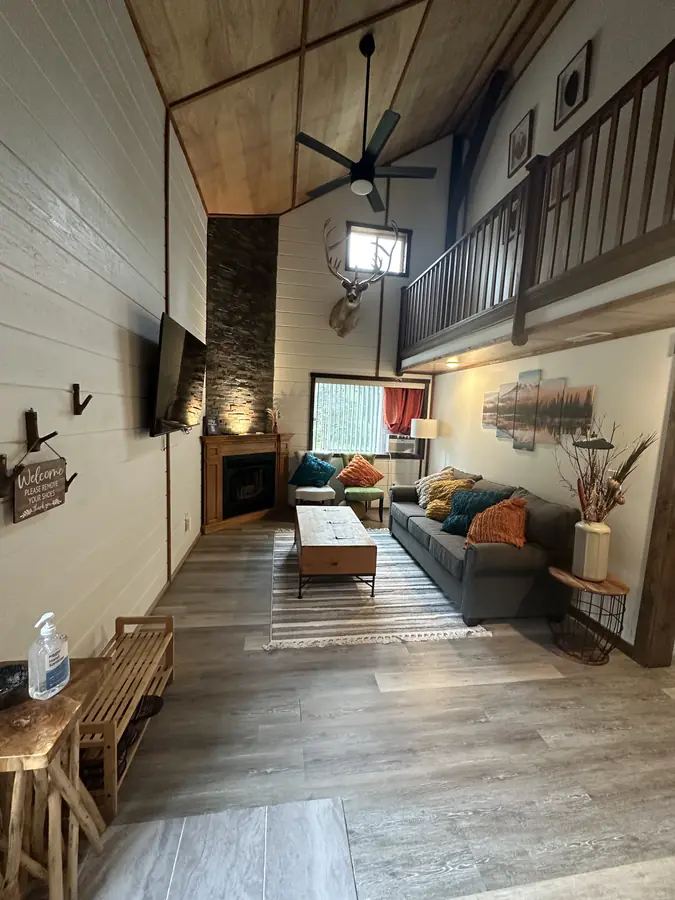 The Baan Rai living room, with a cathedral ceiling, stone fireplace, and open loft