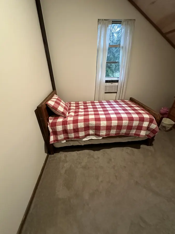 An upstairs twin bedroom with a red gingham quilt
