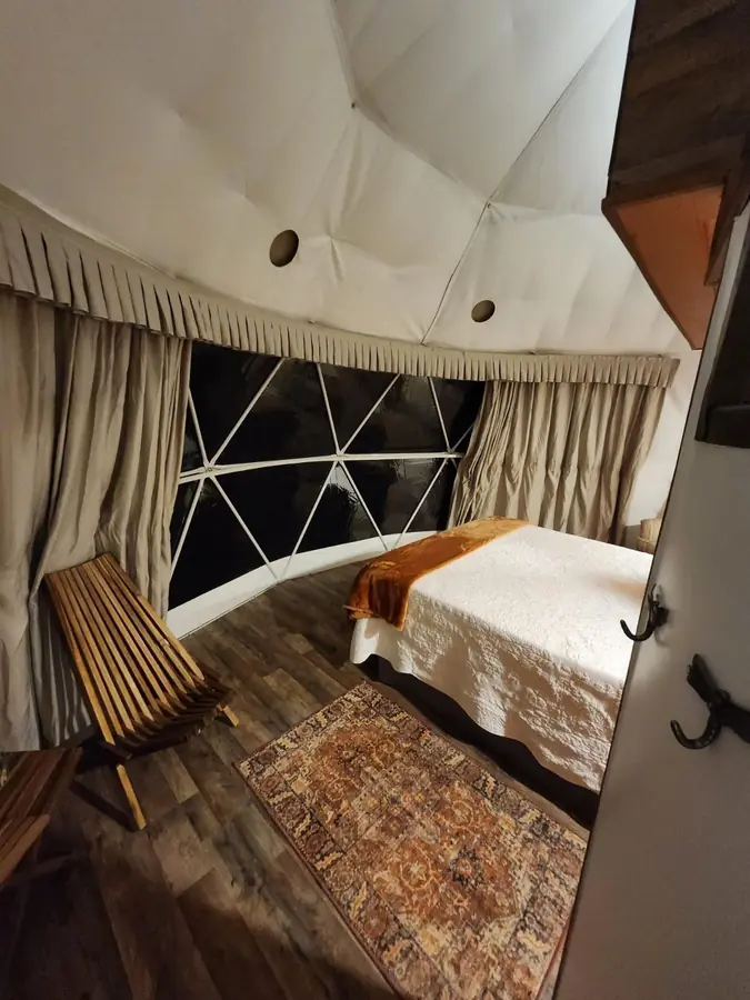 The queen bed beside a curtained wall of triangle windows