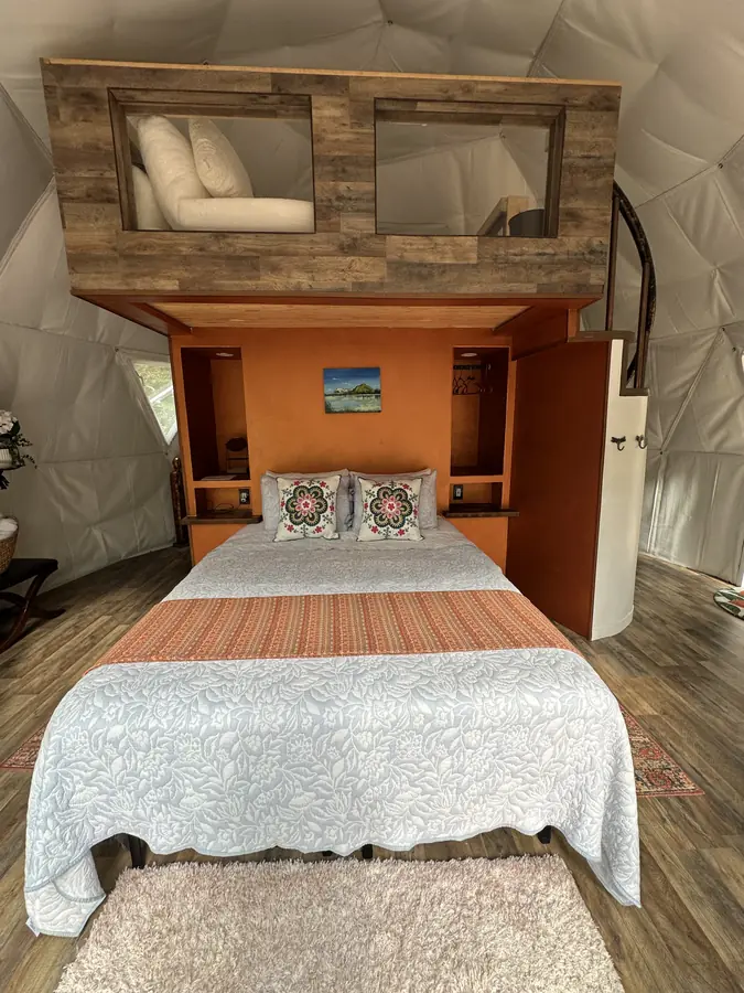 Inside the Dragonfly Yurt: a queen bed with built-in shelves, and a cushioned loft above for kids