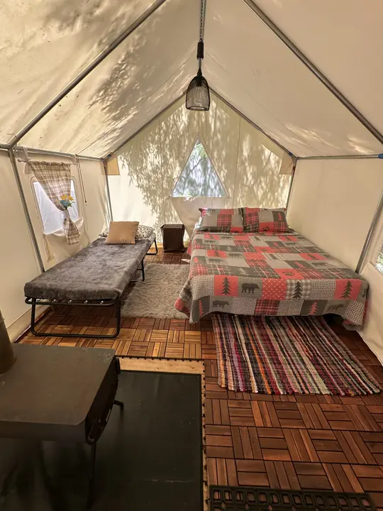 A queen bed and a cot beside the wood stove