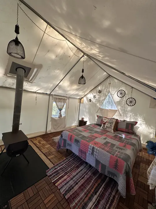 A Fern Gully tent with a queen bed and a wood stove