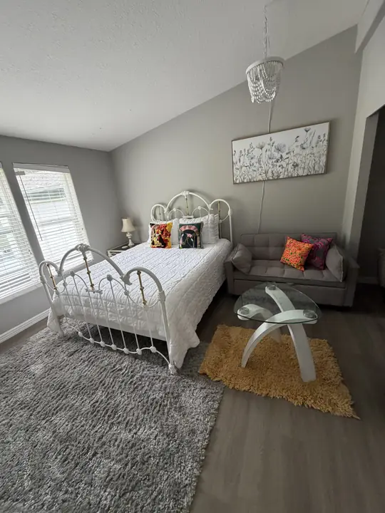 A Lake House bedroom with a white iron bed and crystal chandelier