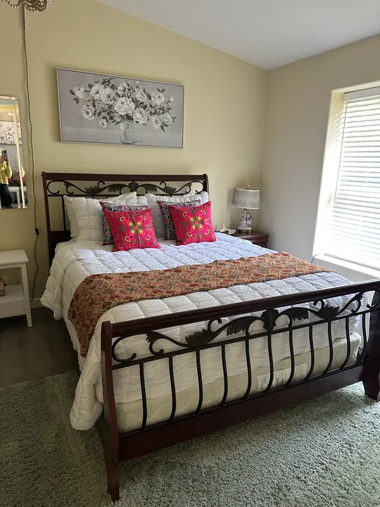 A Lake House bedroom with a wrought-iron sleigh bed and bright pillows