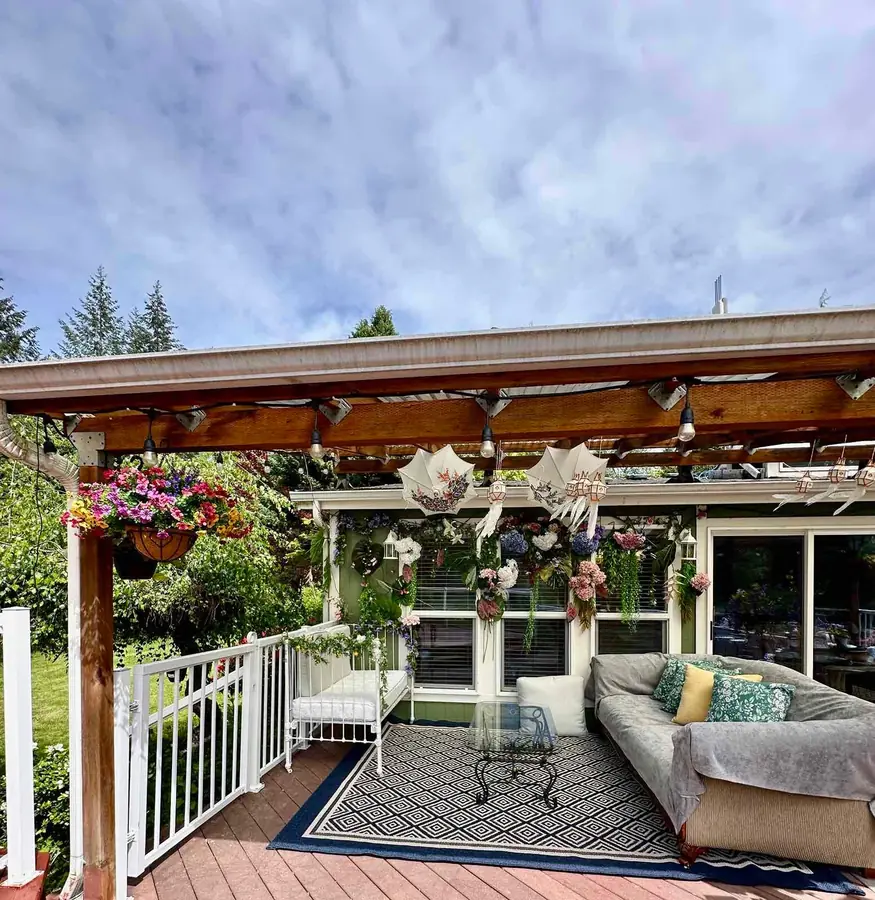 The covered deck, with string lights, hanging flowers, and lounge seating