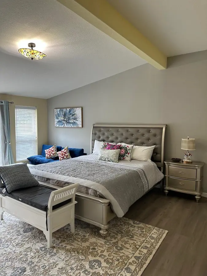 The Lake House master bedroom, with a tufted king bed and stained-glass light
