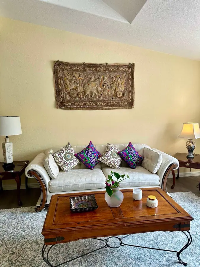 A tufted sofa beneath an embroidered tapestry in the living room