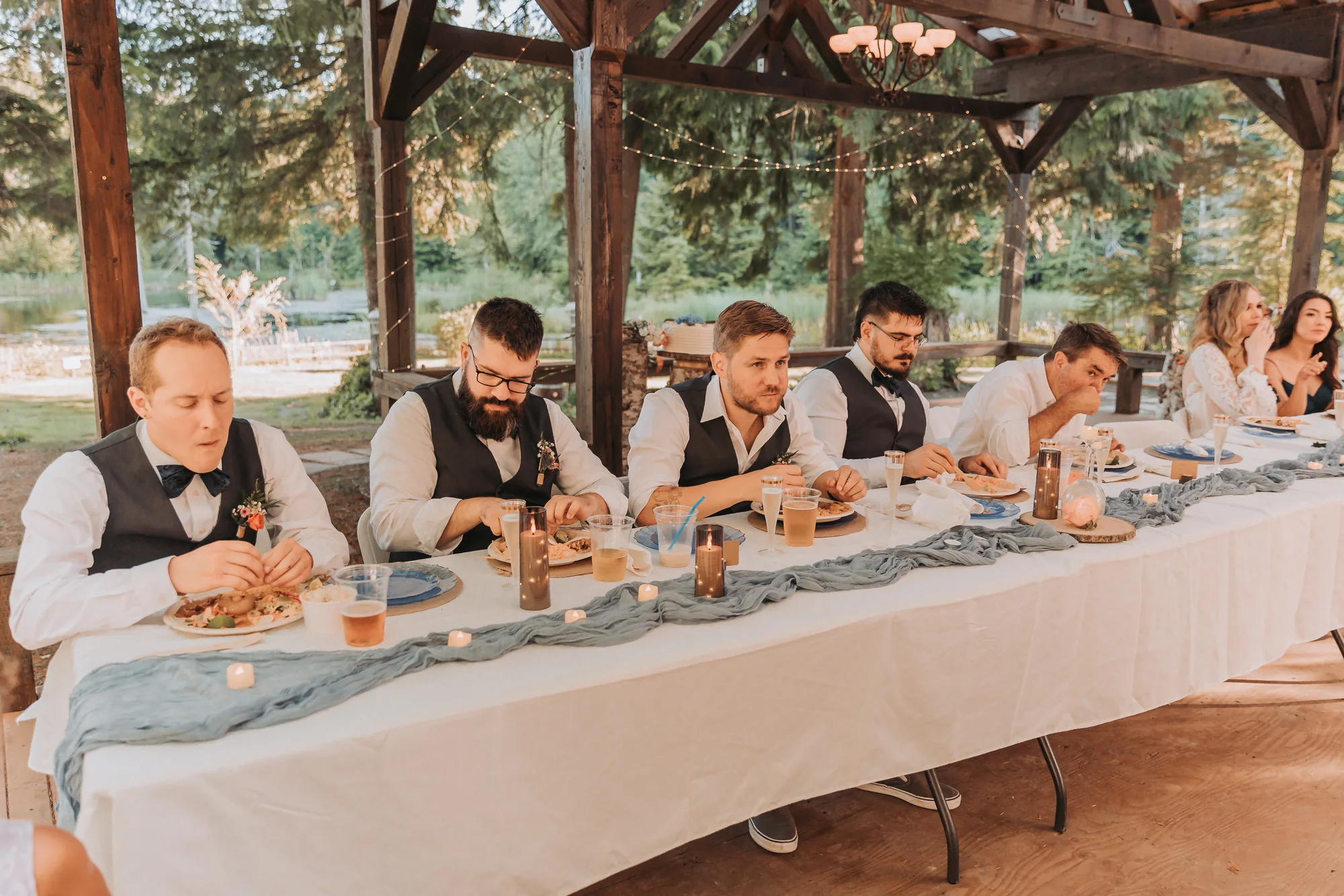 The wedding party at the head table under the patio chandelier