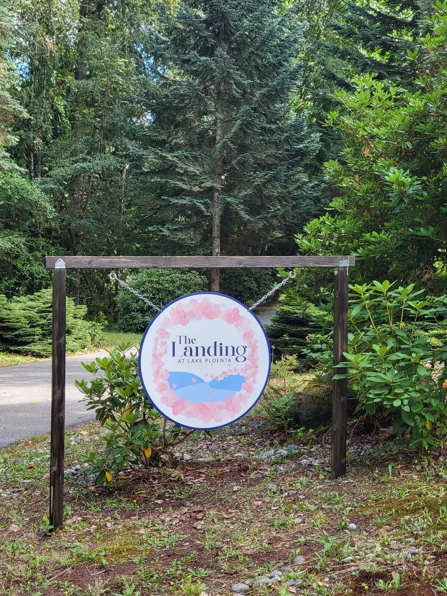 The Landing at Lake Ploenta sign at the property entrance, hanging from a timber frame among the trees