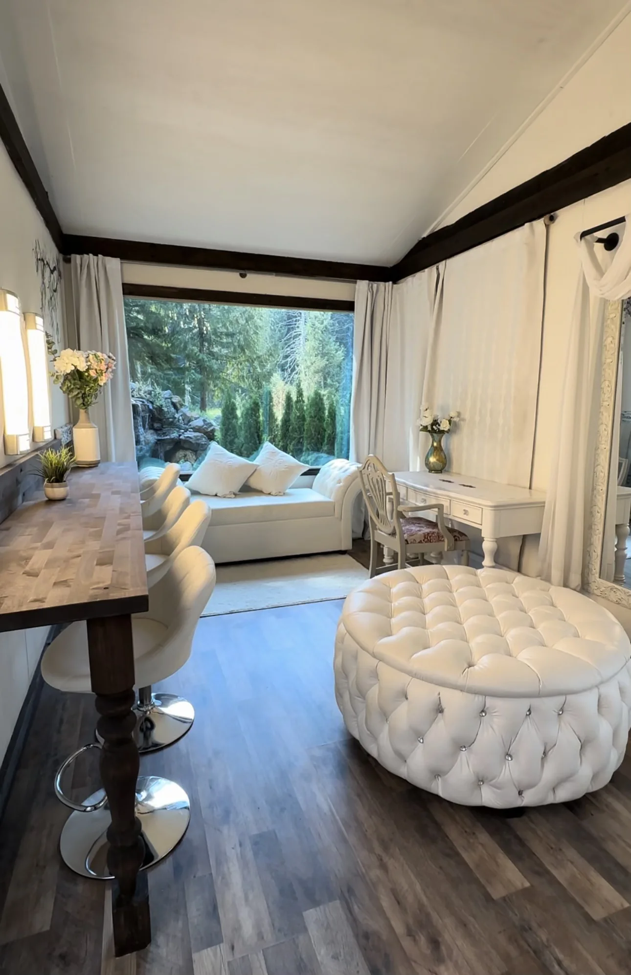 The Bridal Ready Room, with a tufted ottoman, vanity, and a window onto the forest